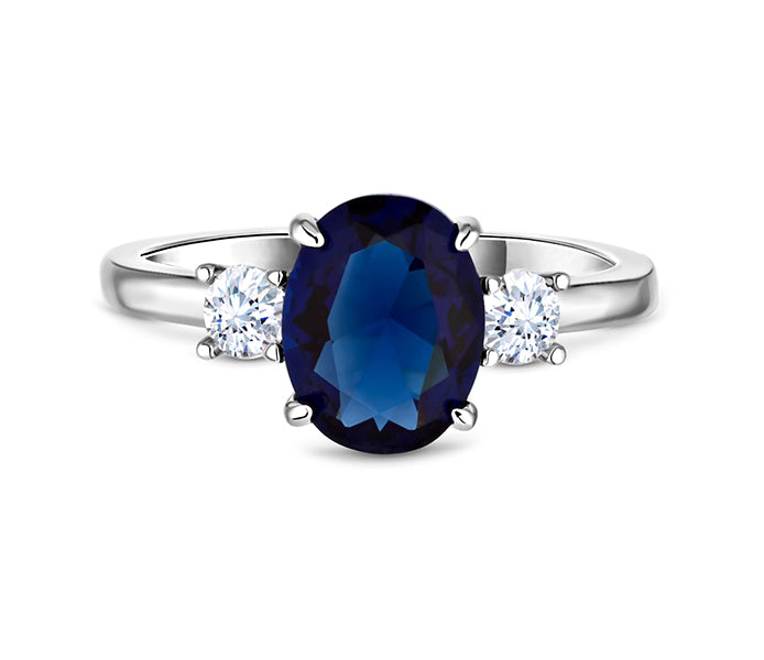 Oval cut blue ring with clear side stones in rhodi