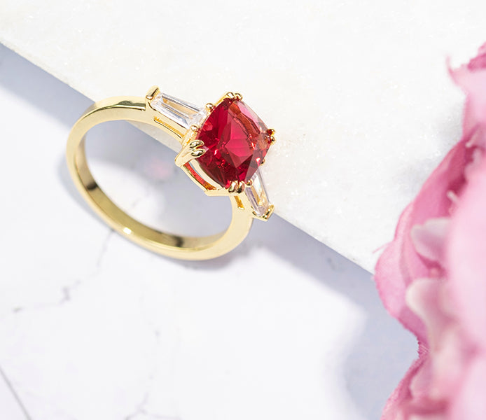 Ruby oval ring with clear side stones in yellow gold plating